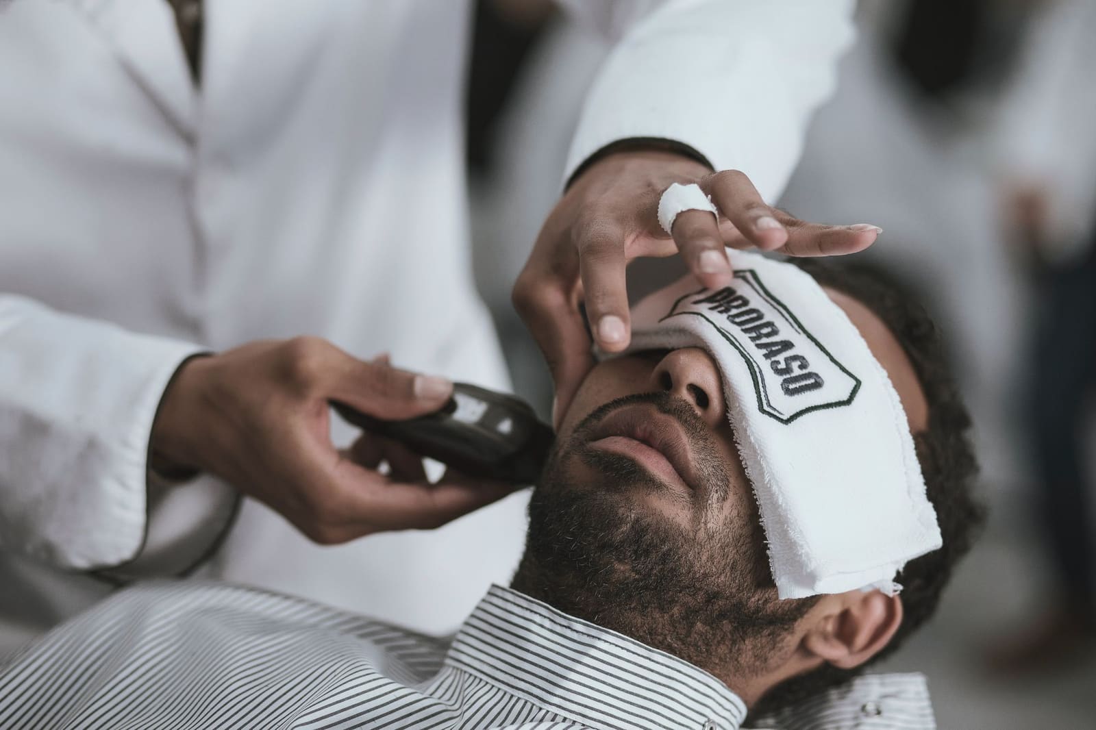 Barber som barberer en mann med elektrisk trimmer