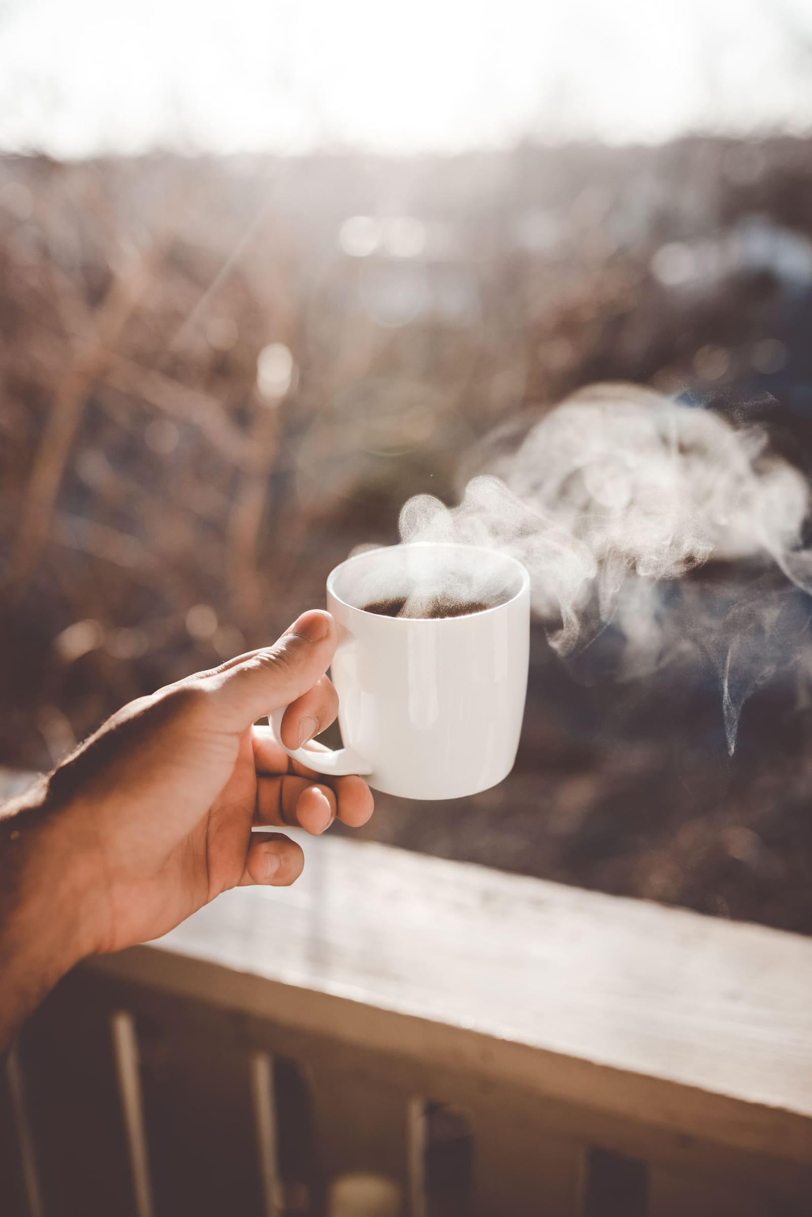 Hånd som holder en kopp med dampende kaffe