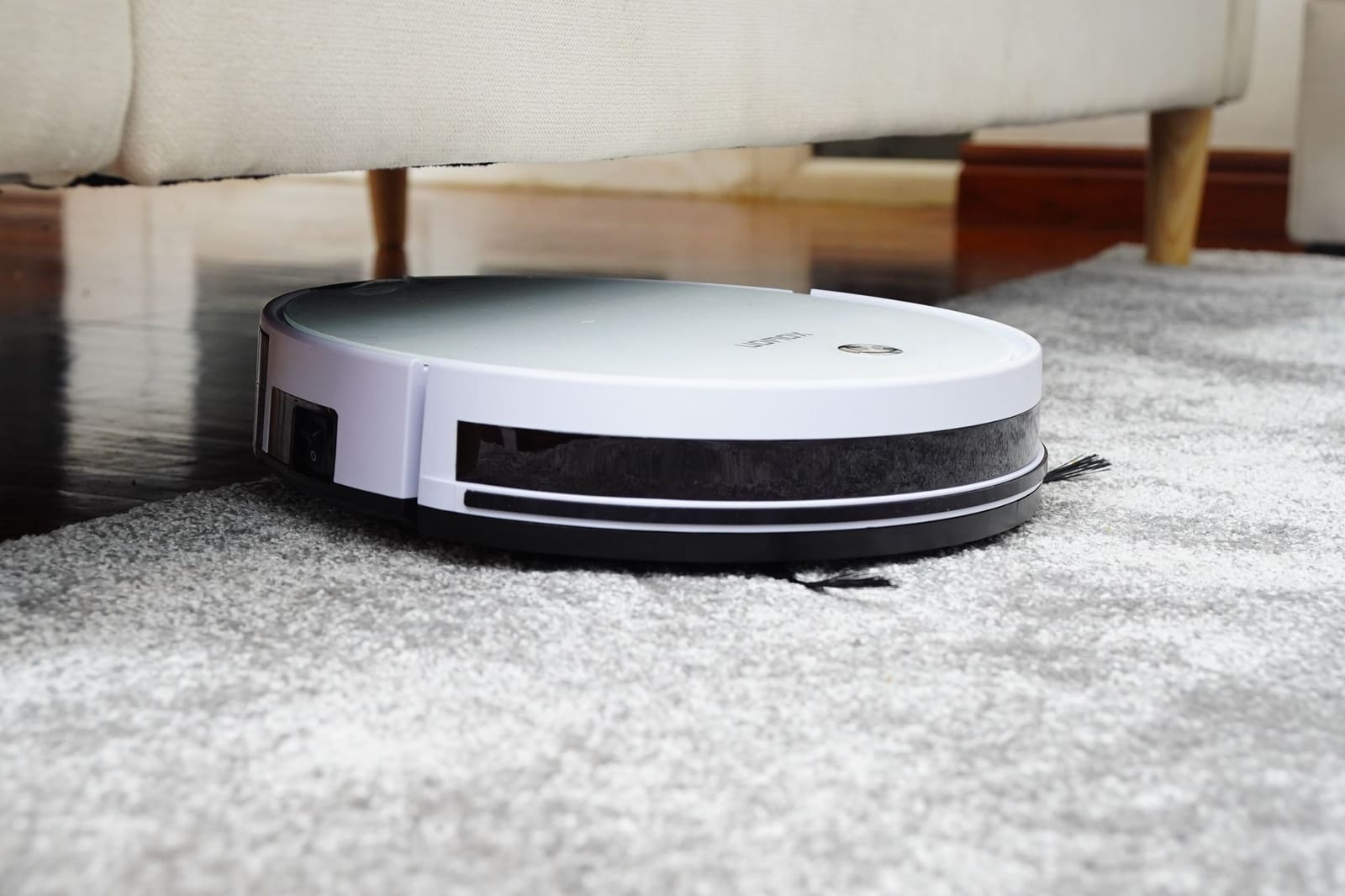 Robotstøvsuger på et teppe under en sofa