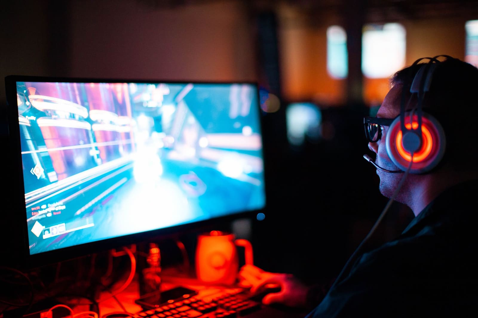 Gamer med belyst headset foran en dataskjerm