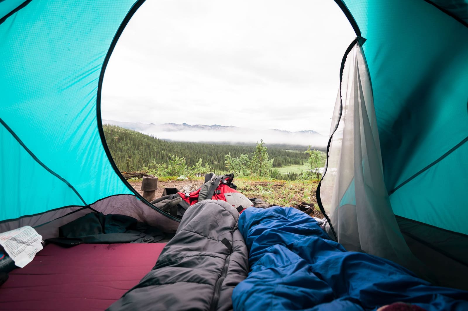 Soveposer i et telt med utsikt mot fjellet