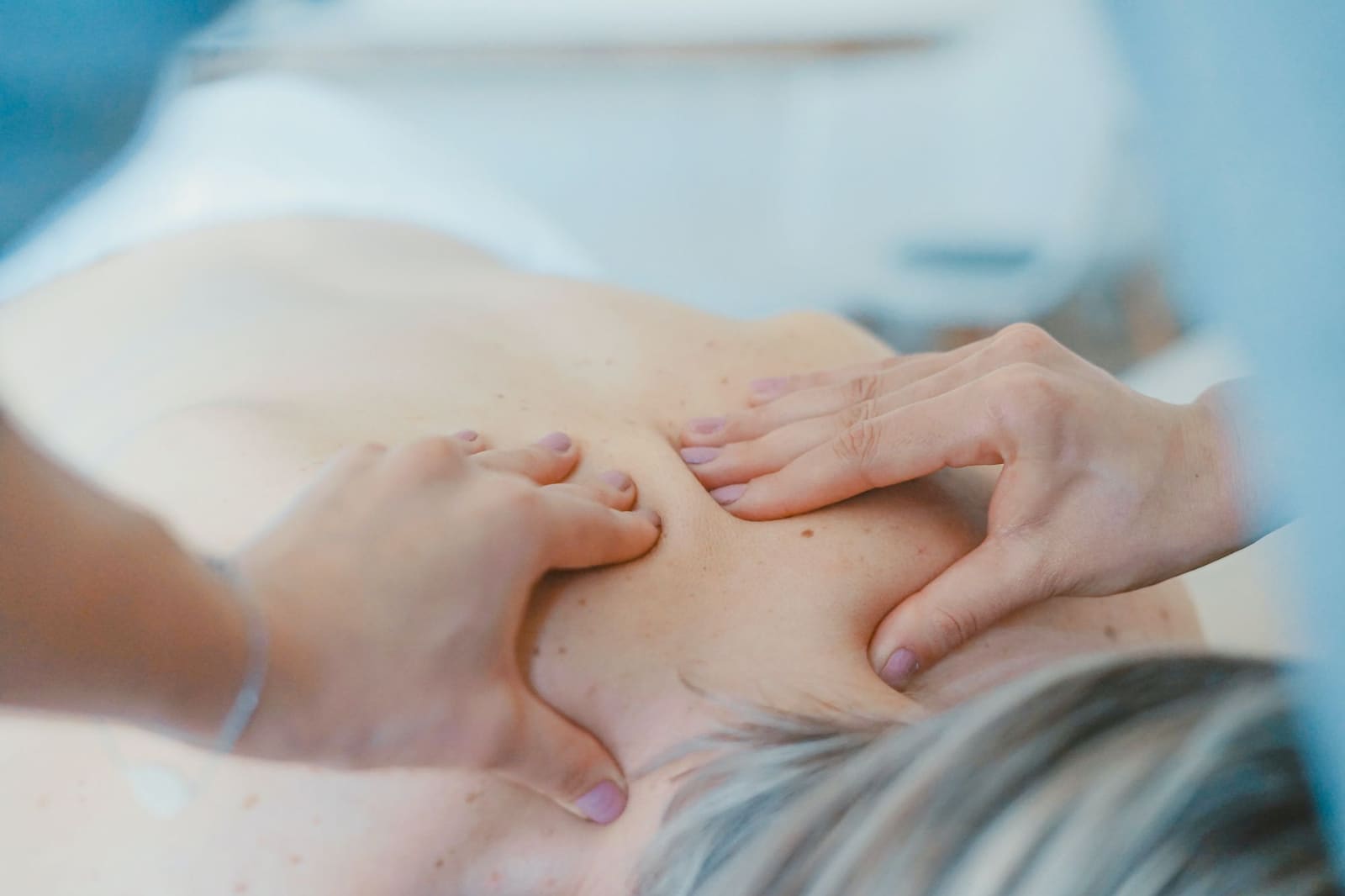 Hender som masserer en persons skulder