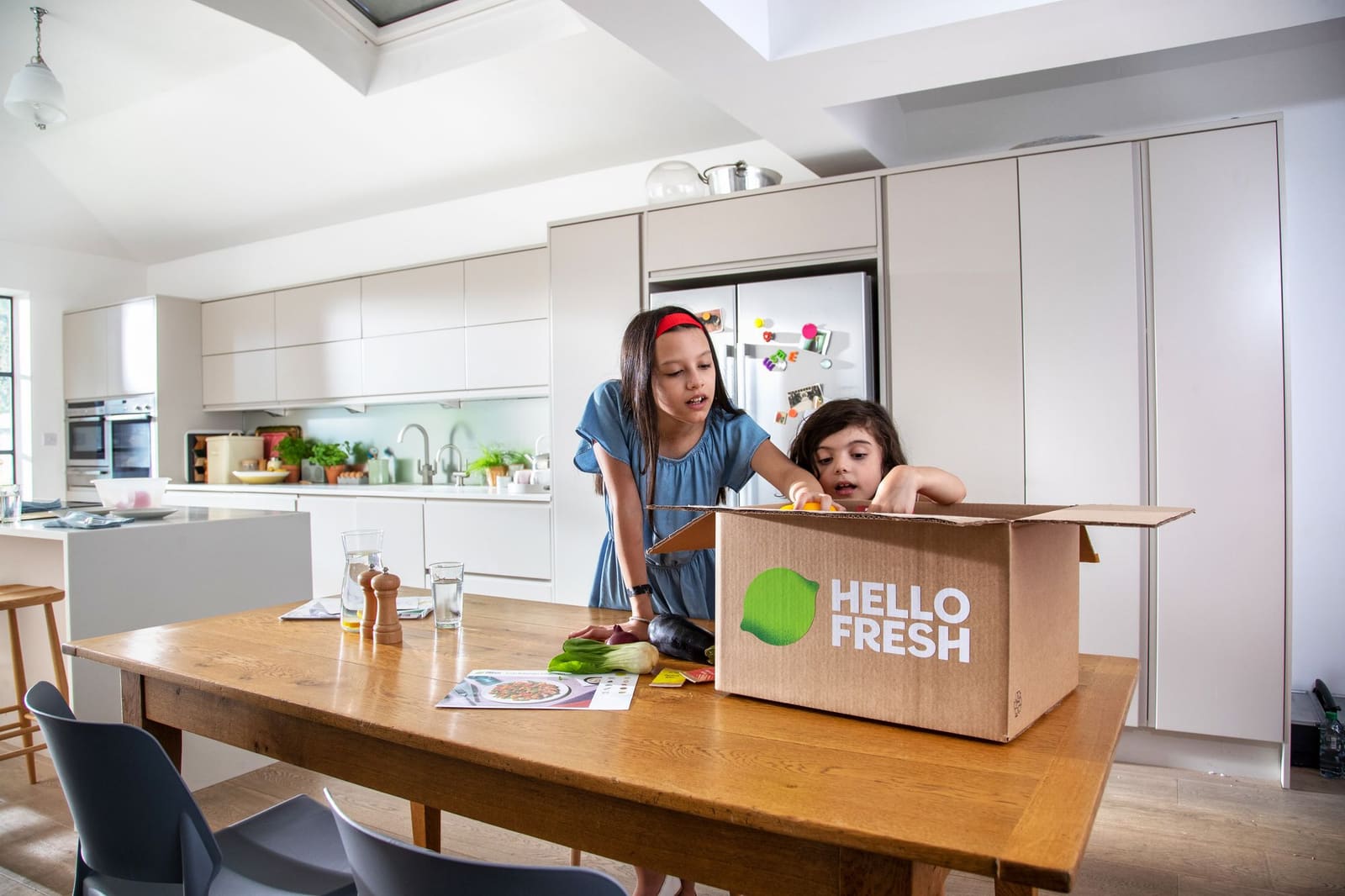 Mor og barn pakker ut en HelloFresh-matkasse på kjøkkenet